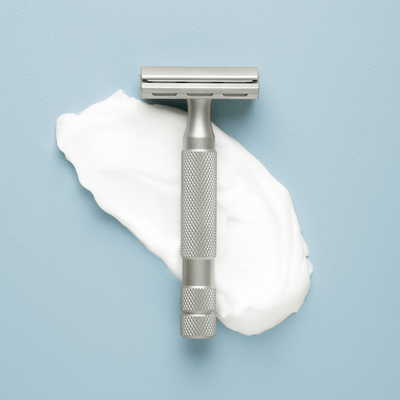 Grooming Products | Craftsman Supply Co. (Razor positioned on top of paper on a light blue flat background)