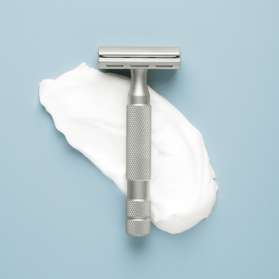 Grooming Products | Craftsman Supply Co. (Razor positioned on top of paper on a light blue flat background)