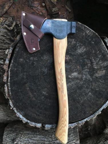 Axes | Craftsman Supply Co. (Metal axe with a light colour gain wood handle with a protective leather covering over the blade sitting on a dark tree stump)