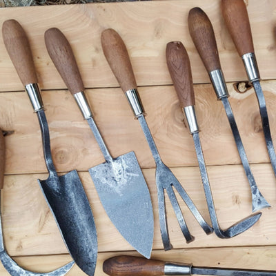 Garden Tools - Craftsman Supply Co. (A collection of different gardening tools laid out on a wooden table.)